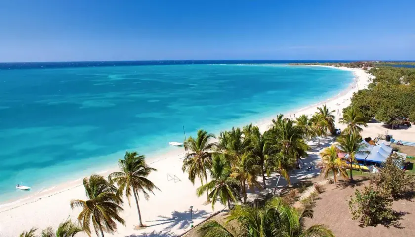 Traumhaftes Kuba im April: Türkisblaues Meer, weißer Sandstrand und Palmen unter strahlend blauem Himmel. Perfektes Wetter für einen Urlaub.