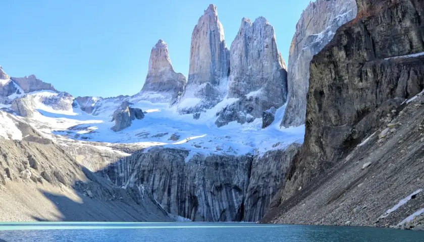 Majestätisches patagonia gebirge mit schneebedeckten Gipfeln, die sich über einem türkisfarbenen See erheben.