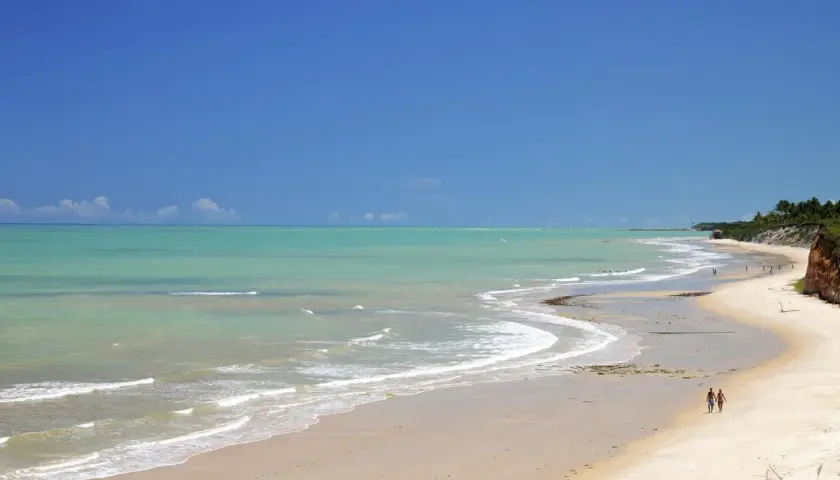 Traumhafter Strand mit türkisfarbenem Wasser und zwei Spaziergängern in Porto Seguro, Bahia.