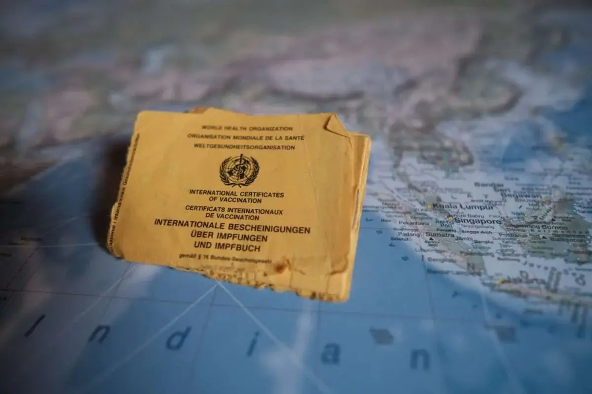 Gelbes Impfbuch auf einer Weltkarte, die Indonesien zeigt. Wichtige Dokumente für Reisen und Impfungen.