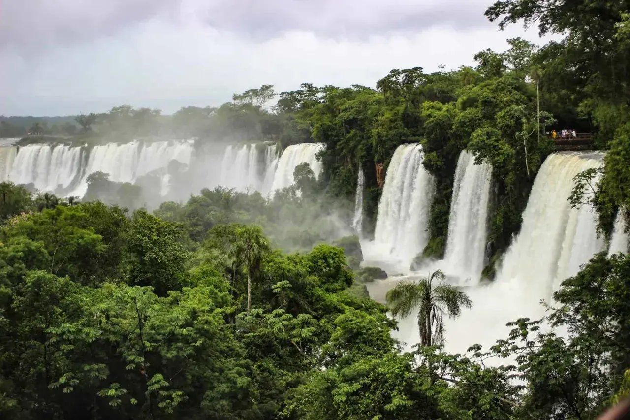 Majestätische Wasserfälle der Foz do Iguaçu stürzen in üppige grüne Vegetation. Besucher genießen die Aussicht von einer Plattform.