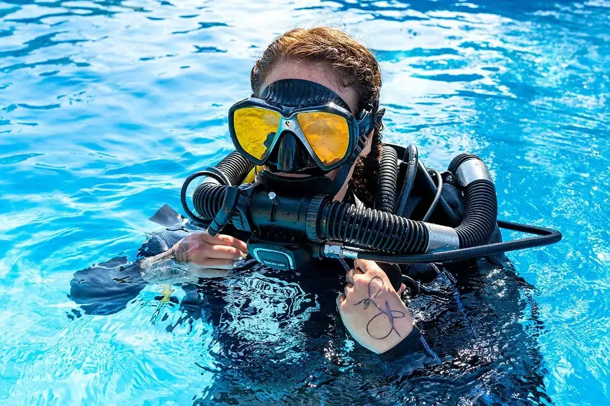 Taucherin mit gelber Maske und Atemregler im klaren Wasser, bereit für das Tauchen auf Bali.