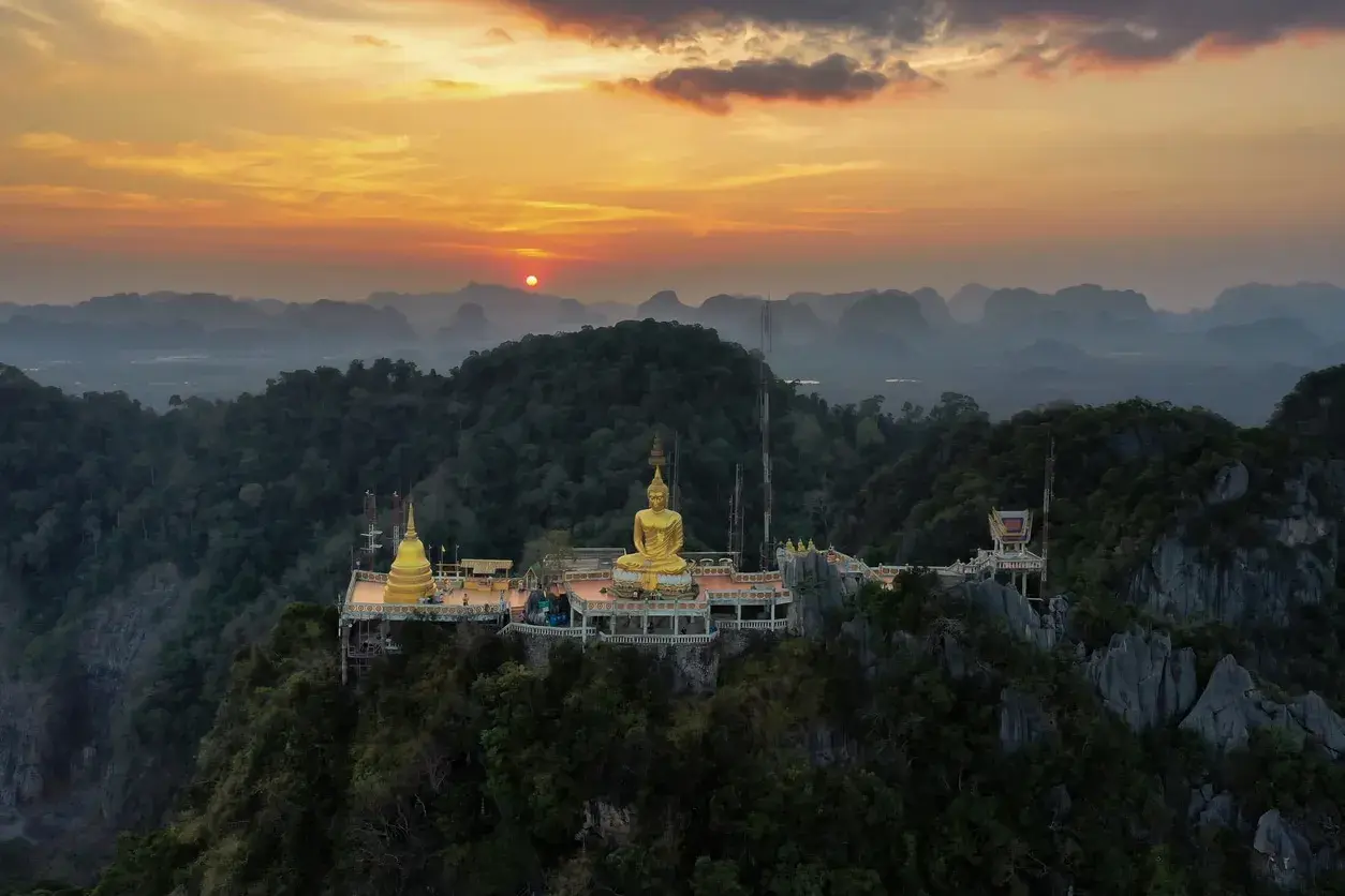 Goldener Buddha auf einem Bergplateau, Teil des Tiger Cave Tempels, bei Sonnenuntergang.