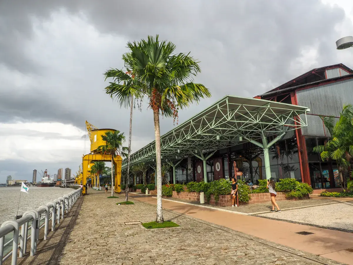 Uferpromenade in Belém, Brasilien, mit Palmen, einem gelben Kran und einem modernen Gebäude.