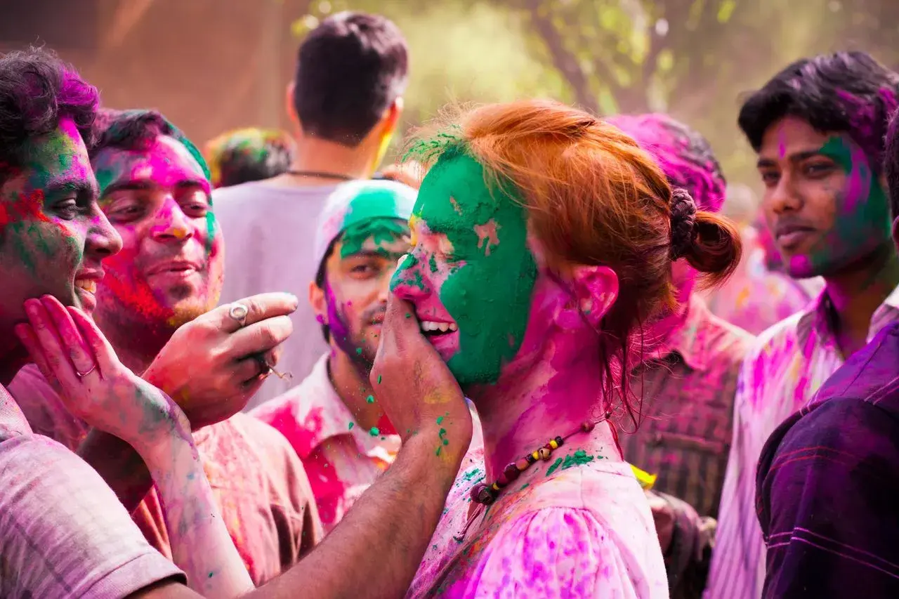 Bunte Gesichter beim Farbenfest in Indien. Menschen lachen und bewerfen sich mit Pulver.