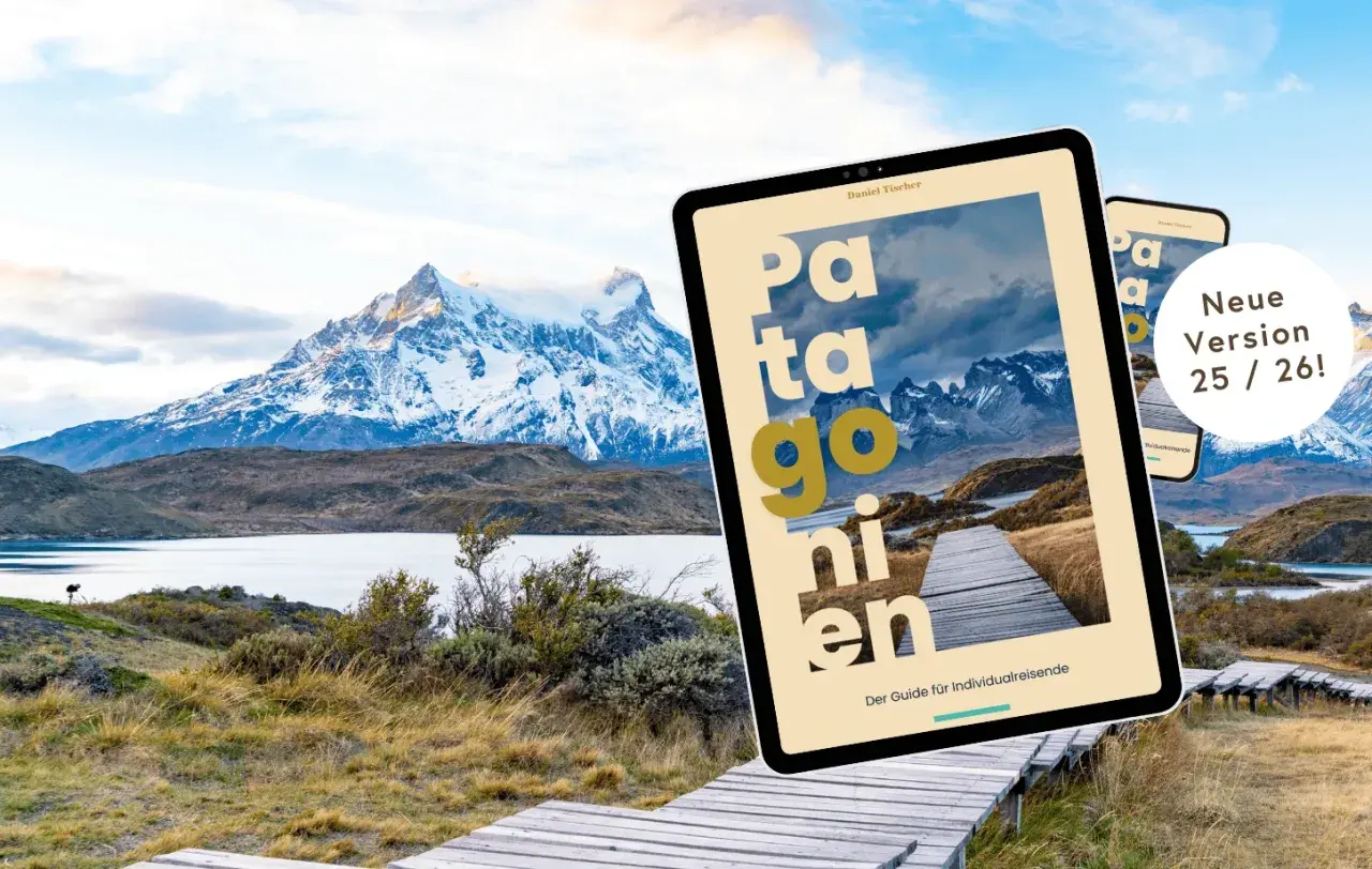 Ein Tablet mit dem Titel "Patagonien" liegt vor einer atemberaubenden Berglandschaft. Der Reiseführer ist die neue Version 25/26.