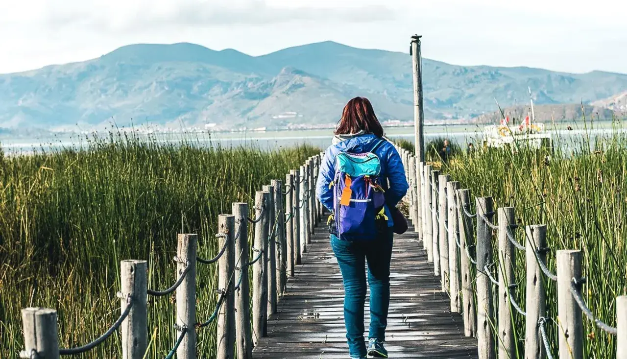 Frau mit Rucksack auf Holzsteg in Peru, genießt die Natur. Peru Sicherheit für Frauen auf Reisen ist gut.