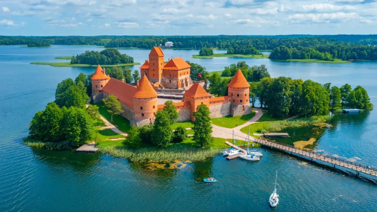 Trakai Burg auf einer Insel im See, umgeben von grünen Bäumen. Perfekt für die beste Reisezeit Baltikum im Sommer.