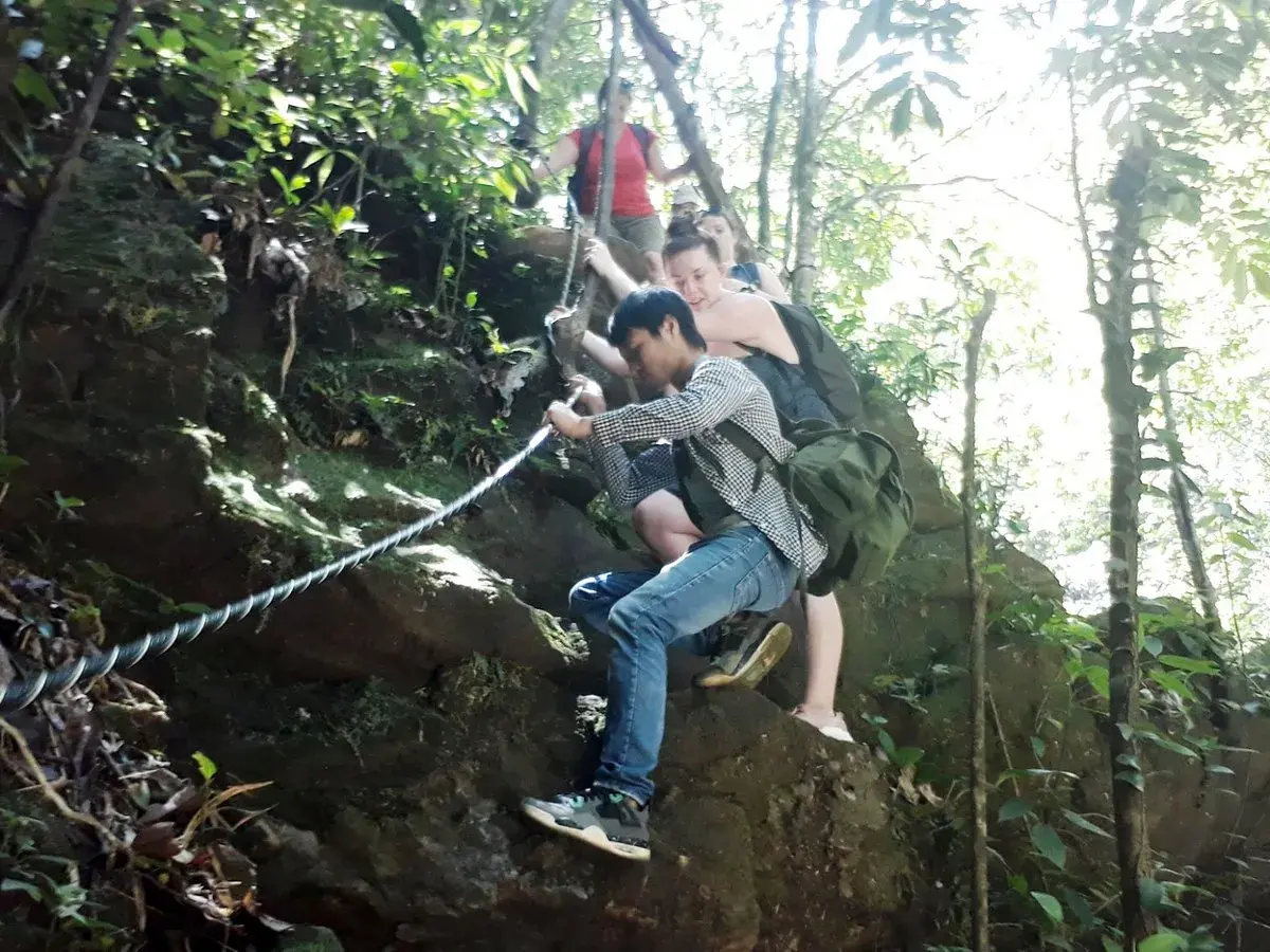 Wanderer klettern mit Seilen einen felsigen Pfad im Bach Ma Nationalpark hinauf.