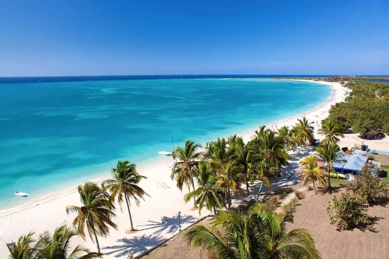 Traumhaftes Kuba im April: Türkisblaues Meer, weißer Sandstrand und Palmen unter strahlend blauem Himmel. Perfektes Wetter für einen Urlaub.
