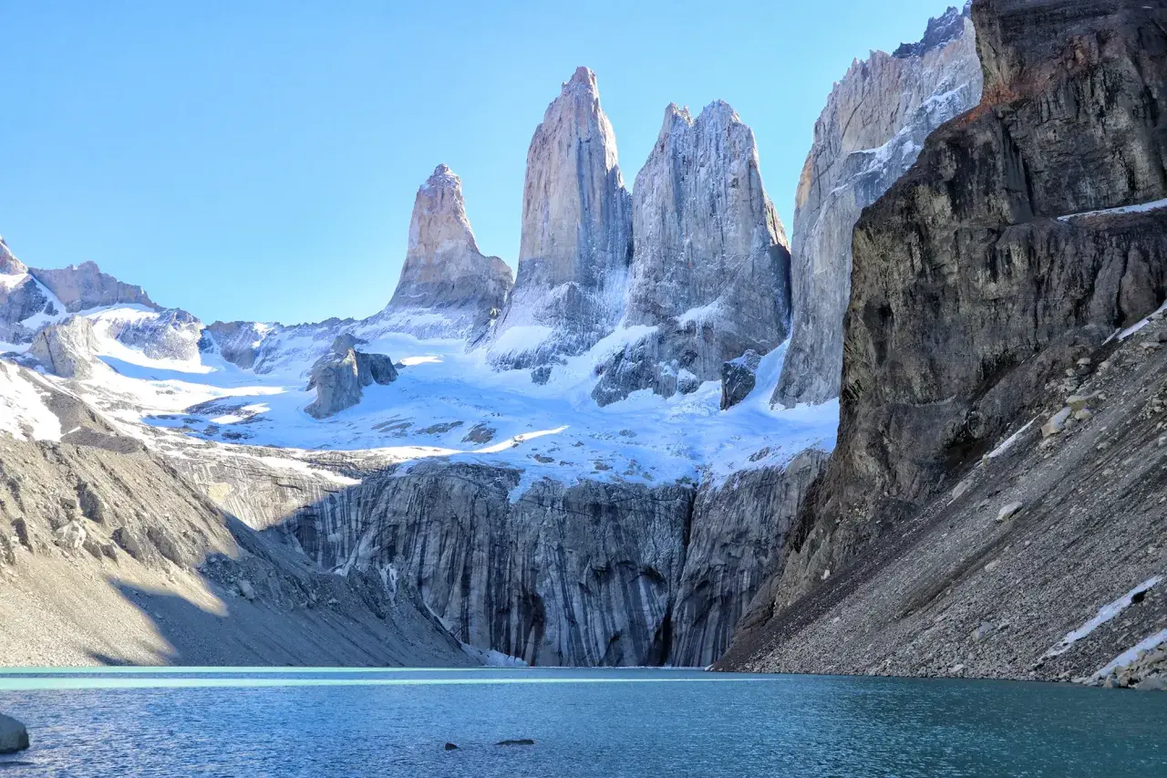 Majestätisches patagonia gebirge mit schneebedeckten Gipfeln, die sich über einem türkisfarbenen See erheben.