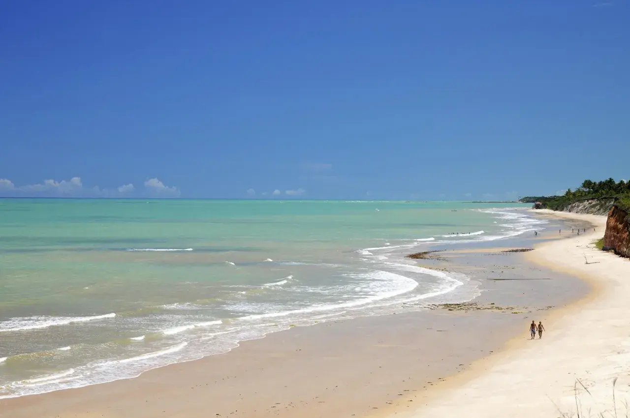 Traumhafter Strand mit türkisfarbenem Wasser und zwei Spaziergängern in Porto Seguro, Bahia.