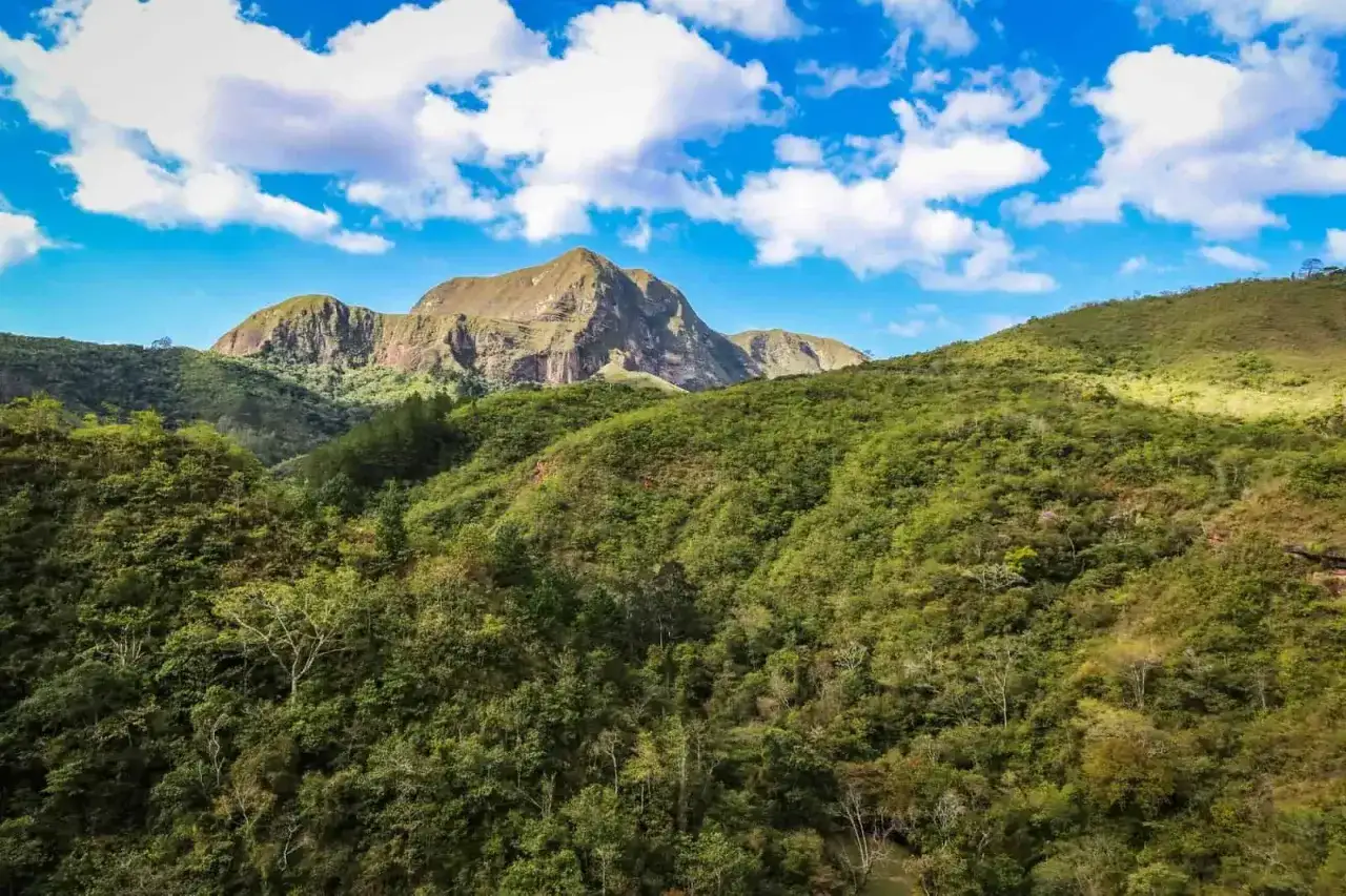 Grüne Hügel und ein majestätischer Berg prägen diese atemberaubende bolivianische Landschaft unter einem strahlend blauen Himmel mit weißen Wolken.