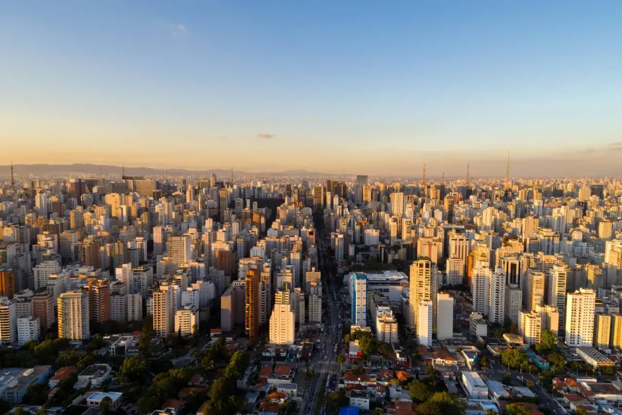 Blick über die weitläufige Stadtlandschaft von São Paulo im goldenen Licht der Abendsonne. Die schiere Größe der Stadt lässt erahnen, wie viel Einwohner São Paulo hat.