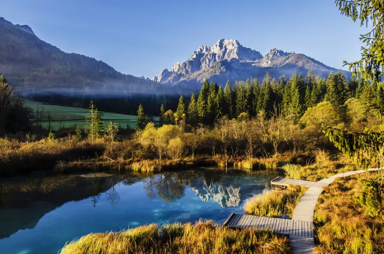Herbstliche Farben am See mit Bergspiegelung. Die beste Reisezeit Slowenien für dieses Panorama ist der Herbst.