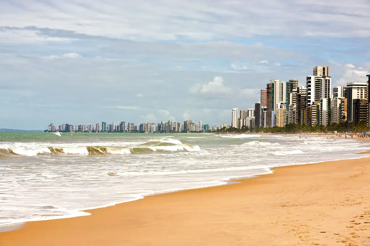 Strand mit Wellen und einer Skyline von Hochhäusern in Recife, Brasilien.