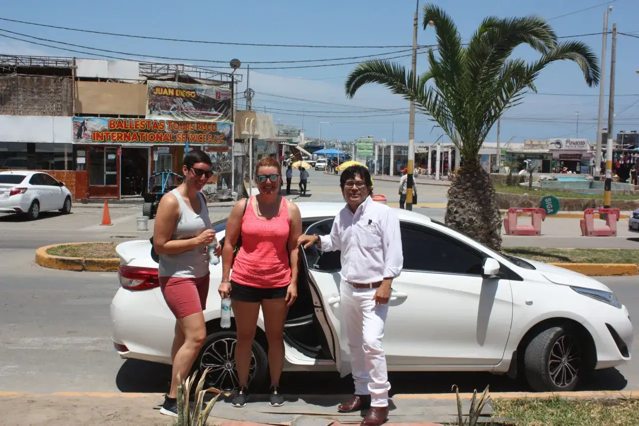 Zwei Frauen und ein Mann stehen vor einem weißen Auto in Peru. Sie wirken entspannt, was auf eine gute Sicherheit für Frauen hindeutet.