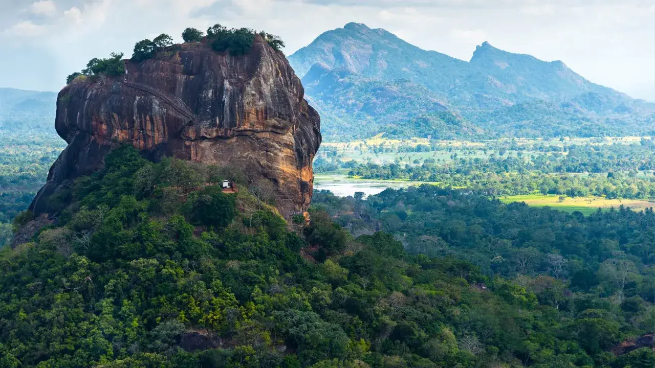 Majestätische Felsenfestung Sigiriya Sri Lanka, umgeben von üppigem Grün und Bergen. Treppen führen zum Gipfel.