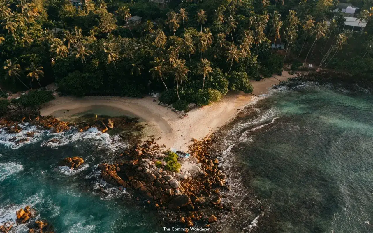 Traumhafte Bucht mit Palmen und Felsen an der Küste von Sri Lanka im April. Eine kleine Bucht mit Sandstrand und türkisfarbenem Wasser.