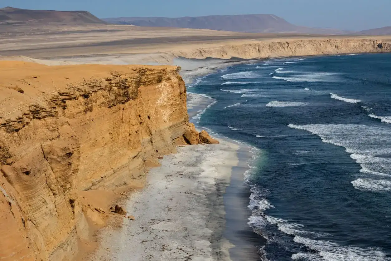 Steile Felsklippen treffen auf das Meer. Das Peru Wetter im Dezember ist hier sonnig und die Wellen brechen an der K&uuml;ste.