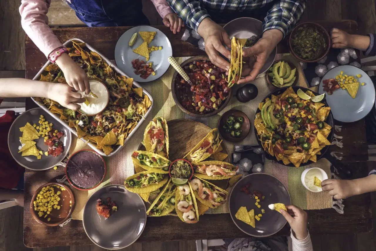Familie isst Nachos und Tacos. Was sollte man in Mexiko nicht essen? Wahrscheinlich nichts von diesem köstlichen Tisch!