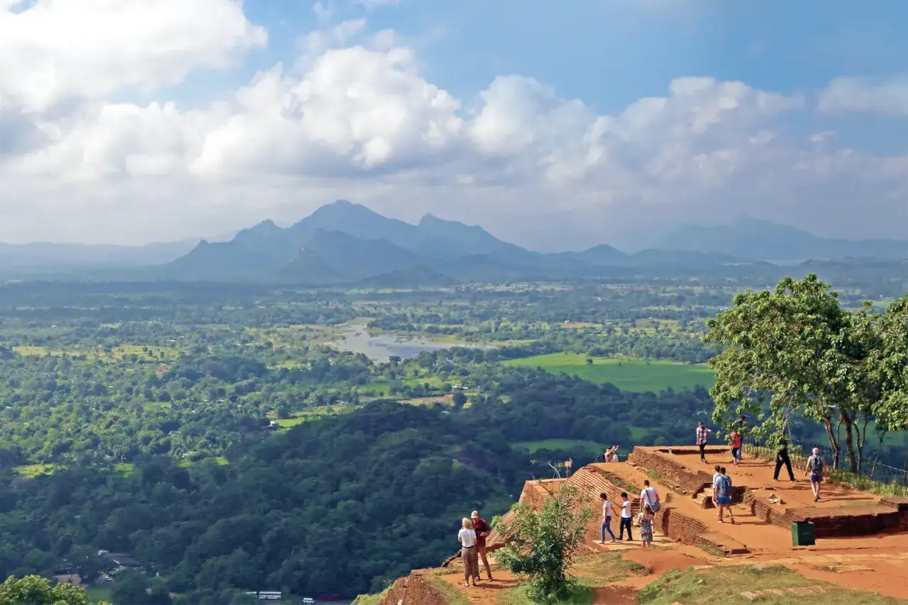 Touristen genießen die atemberaubende Aussicht vom Sigiriya Sri Lanka, einem Felsenplateau mit üppiger Landschaft und Bergen im Hintergrund.