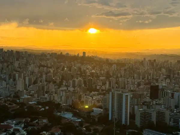 Sonnenuntergang über Belo Horizonte, Brasilien. Die Stadt erstreckt sich unter einem goldenen Himmel, der von Wolken durchzogen ist.
